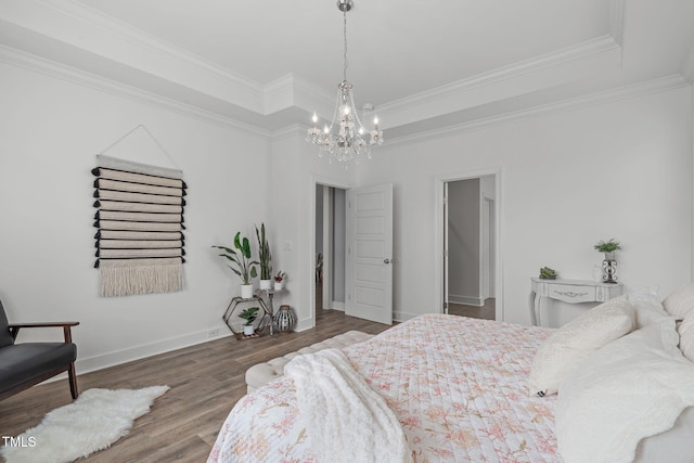 bedroom featuring crown molding, hardwood / wood-style floors, a tray ceiling, and a notable chandelier