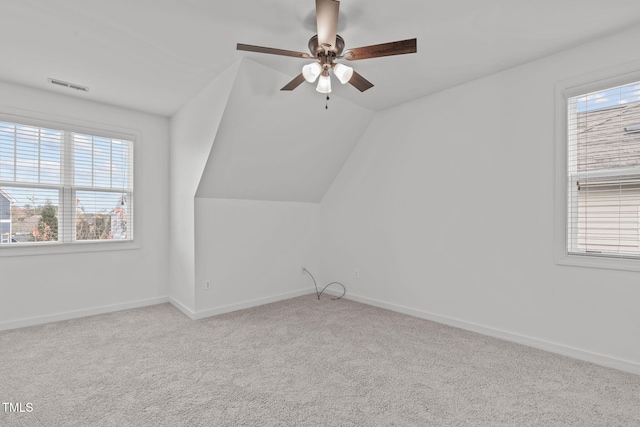 bonus room featuring ceiling fan, light colored carpet, a healthy amount of sunlight, and lofted ceiling