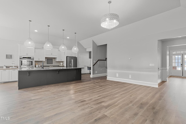 kitchen featuring pendant lighting, white cabinetry, an island with sink, a kitchen bar, and stainless steel appliances