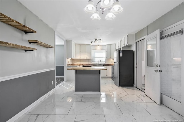 kitchen with stainless steel refrigerator, sink, and white cabinets