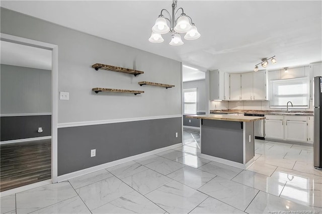 kitchen featuring white cabinetry, a center island, hanging light fixtures, a chandelier, and appliances with stainless steel finishes