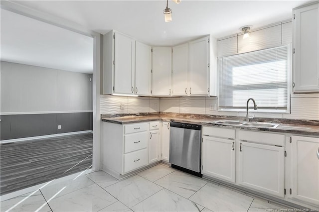 kitchen with stainless steel dishwasher, backsplash, white cabinets, and sink