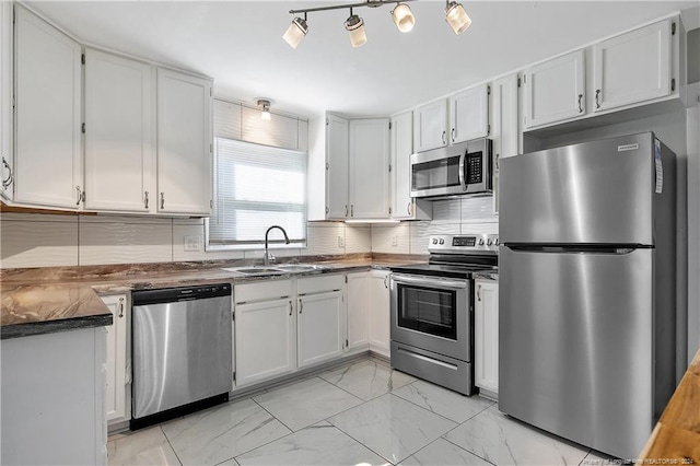 kitchen featuring decorative backsplash, sink, white cabinets, and appliances with stainless steel finishes