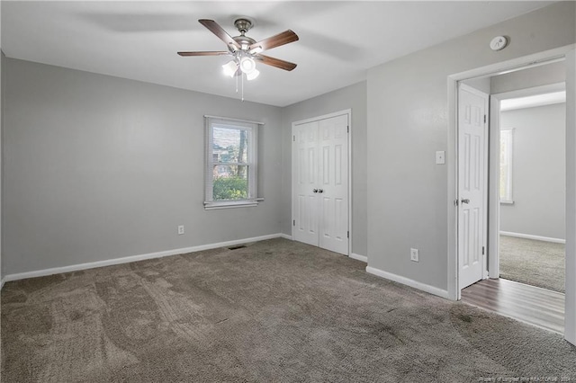 unfurnished bedroom with dark colored carpet, ceiling fan, and a closet