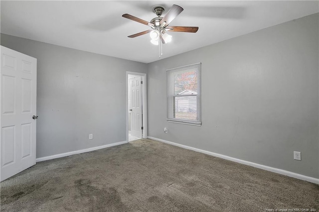 empty room with dark colored carpet and ceiling fan