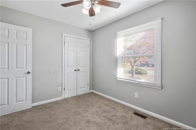 unfurnished bedroom with ceiling fan, light colored carpet, and a closet