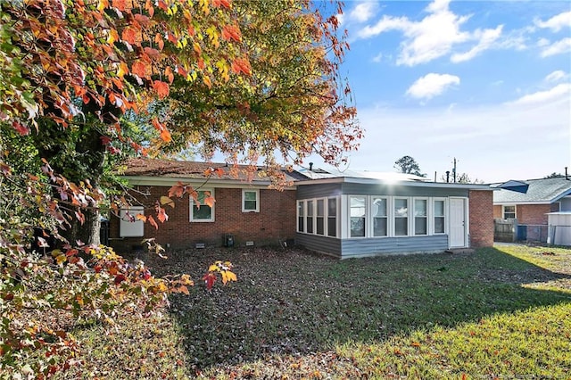 back of property with a sunroom and a lawn