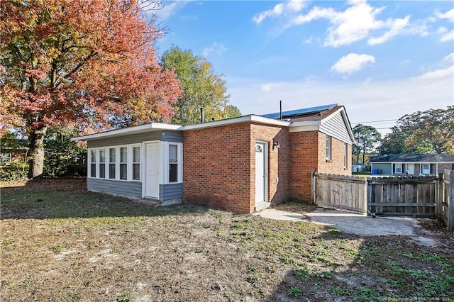 rear view of property featuring solar panels and a lawn