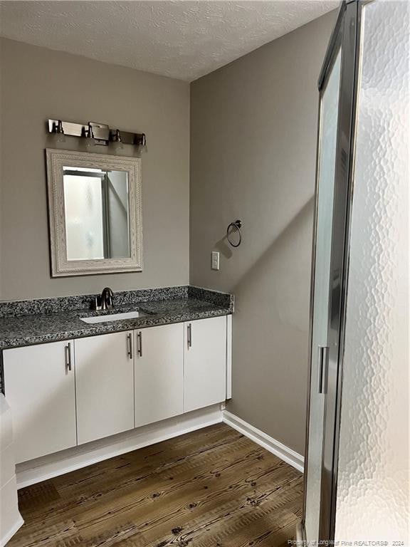 bathroom featuring vanity, wood-type flooring, and a textured ceiling