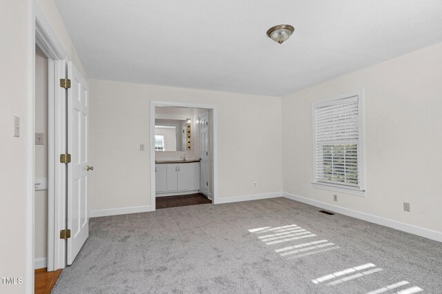 1204 Breedlove Rd, Nashville, NC 27856 - unfurnished bedroom with carpet flooring, multiple windows, baseboards, and ensuite bath