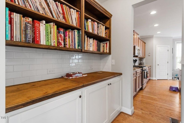 interior space featuring butcher block counters, light hardwood / wood-style floors, white cabinets, backsplash, and stainless steel appliances