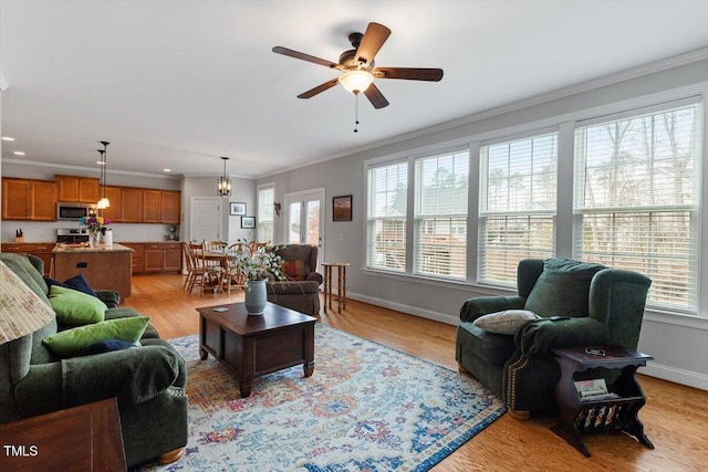 living room with ceiling fan, crown molding, and light wood-type flooring