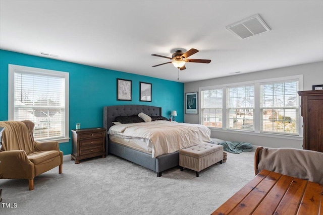 bedroom with ceiling fan, light carpet, and multiple windows