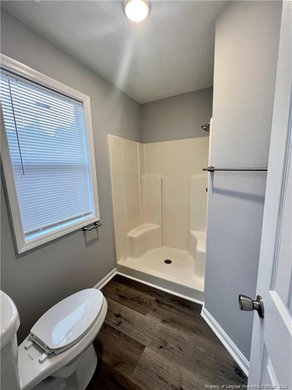 bathroom with toilet, wood-type flooring, and walk in shower