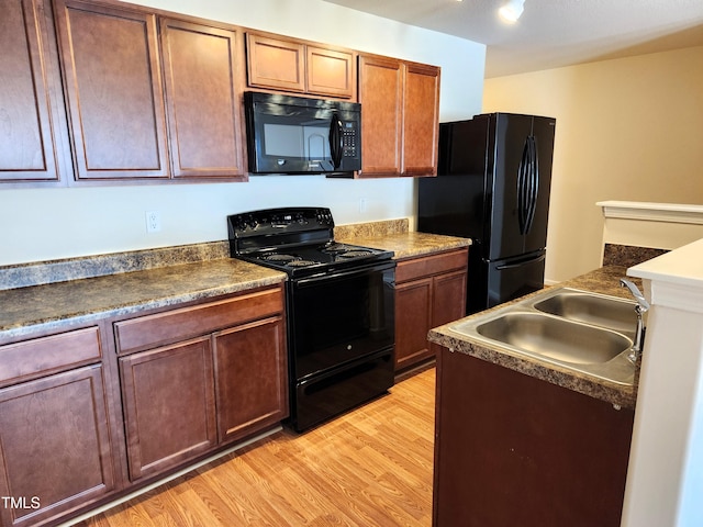 kitchen featuring black appliances, light wood-type flooring, and sink