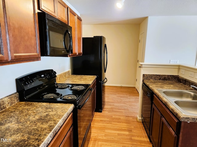 kitchen featuring sink, light wood-type flooring, and black appliances