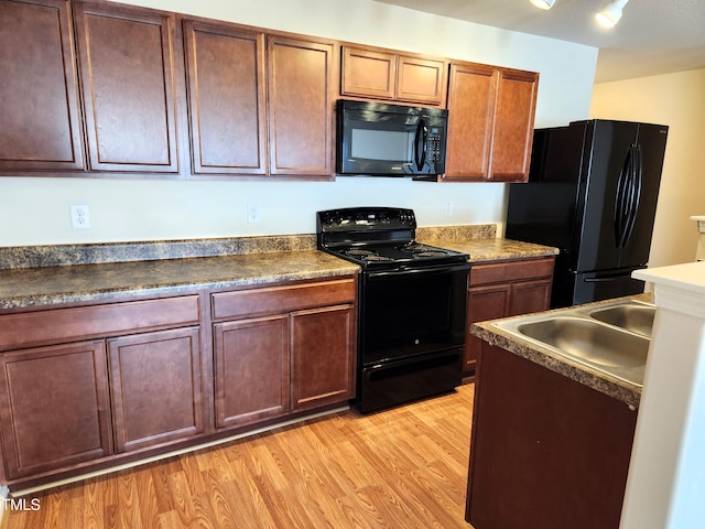 kitchen with black appliances, light hardwood / wood-style floors, and sink