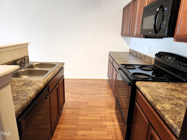 kitchen featuring sink, black appliances, and light wood-type flooring