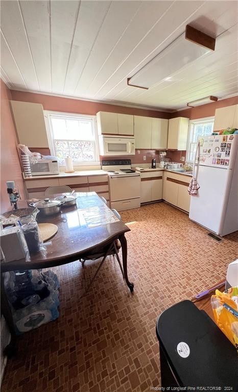 kitchen featuring crown molding, cream cabinets, and white appliances