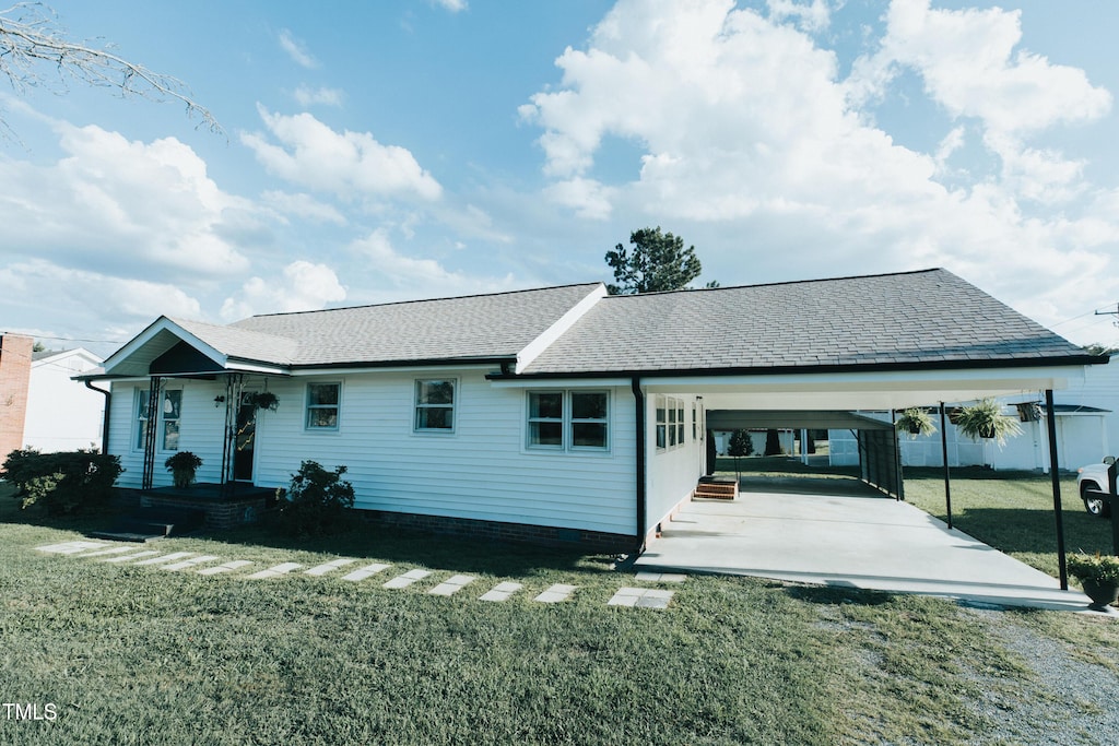 rear view of property featuring a lawn and a carport