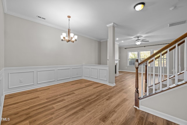 spare room with hardwood / wood-style flooring, ceiling fan with notable chandelier, ornamental molding, and ornate columns