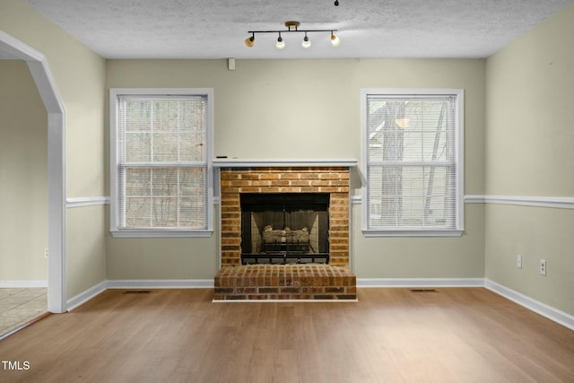 unfurnished living room with a textured ceiling, light hardwood / wood-style floors, and a fireplace