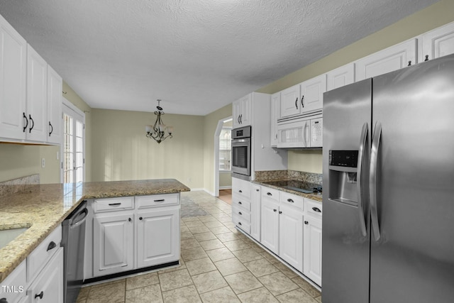 kitchen with white cabinetry, stainless steel appliances, stone countertops, and a notable chandelier