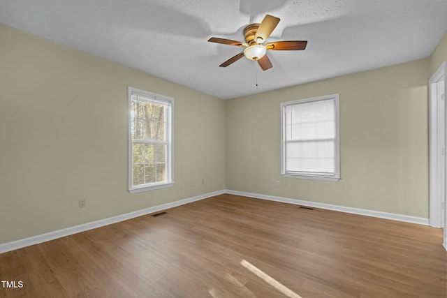 empty room with a textured ceiling, light wood-type flooring, and ceiling fan