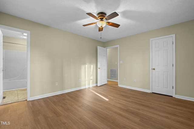 unfurnished bedroom featuring ceiling fan, wood-type flooring, and ensuite bath