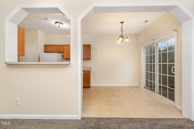 kitchen featuring a notable chandelier, white fridge, light carpet, and hanging light fixtures