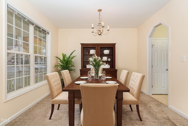 carpeted dining room with an inviting chandelier