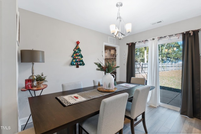 dining space featuring hardwood / wood-style floors and an inviting chandelier