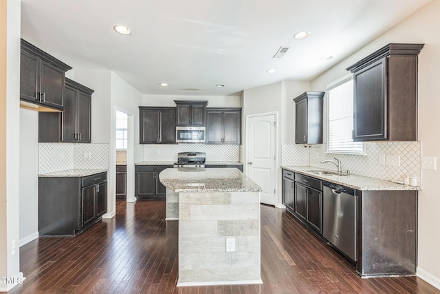 kitchen featuring a center island, sink, dark hardwood / wood-style floors, decorative backsplash, and appliances with stainless steel finishes