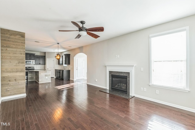 unfurnished living room with a fireplace, dark hardwood / wood-style floors, a wealth of natural light, and ceiling fan