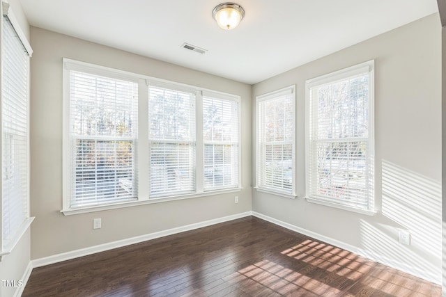 empty room with plenty of natural light and dark wood-type flooring