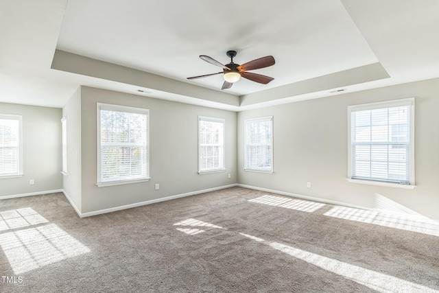 carpeted spare room featuring ceiling fan and a raised ceiling