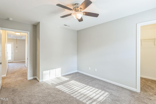 unfurnished bedroom featuring a walk in closet, ceiling fan, a closet, and light colored carpet