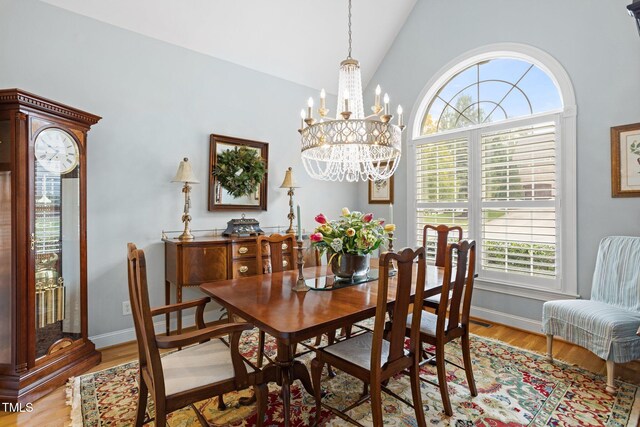 dining area with plenty of natural light, a chandelier, vaulted ceiling, and light wood-type flooring