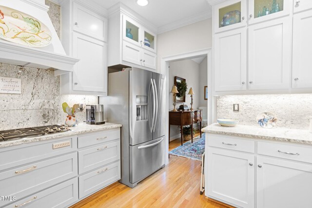 kitchen with premium range hood, crown molding, light hardwood / wood-style flooring, white cabinetry, and stainless steel appliances