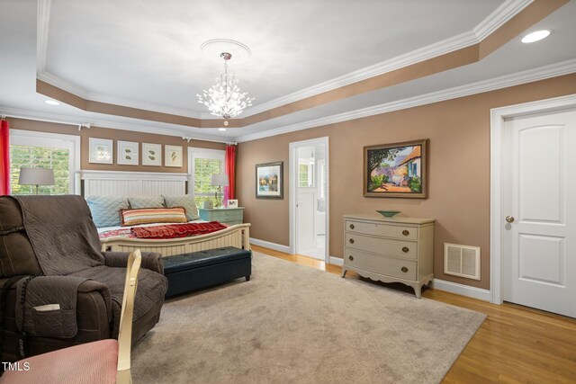 bedroom featuring a chandelier, light hardwood / wood-style flooring, a raised ceiling, and ornamental molding