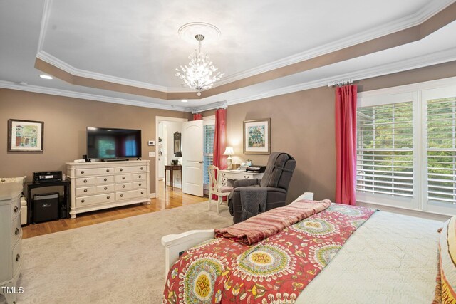 bedroom featuring light hardwood / wood-style floors, an inviting chandelier, ornamental molding, and a tray ceiling