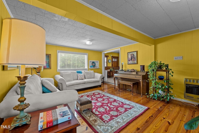 living room featuring hardwood / wood-style floors, wooden walls, heating unit, and crown molding