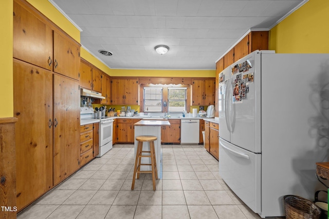 kitchen with a kitchen bar, white appliances, a center island, and light tile patterned flooring