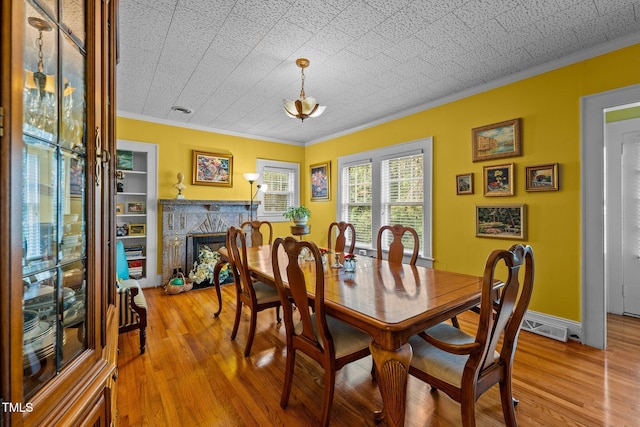 dining room featuring a textured ceiling, light hardwood / wood-style flooring, and crown molding