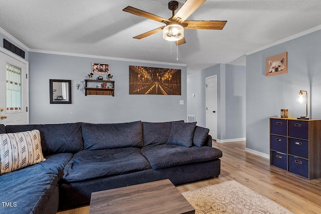 living room featuring ceiling fan, crown molding, light wood-type flooring, and a textured ceiling