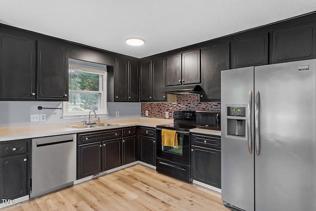 kitchen with tasteful backsplash, sink, black appliances, and light hardwood / wood-style flooring