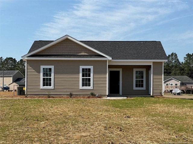 view of front of home featuring roof with shingles and a front yard