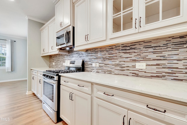 kitchen with tasteful backsplash, crown molding, light stone counters, and appliances with stainless steel finishes