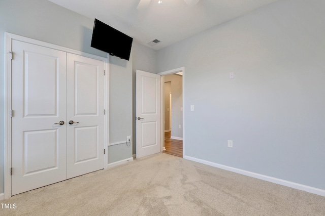 unfurnished bedroom with ceiling fan, light colored carpet, and a closet