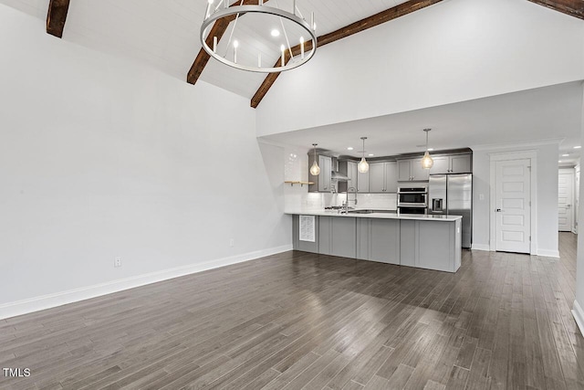 kitchen with gray cabinetry, stainless steel appliances, a chandelier, kitchen peninsula, and beamed ceiling